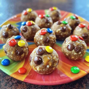 To make these tasty bites, gather these simple ingredients: - 1 cup rolled oats - 1/2 cup creamy peanut butter - 1/3 cup honey or maple syrup - 1/2 cup mini chocolate chips - 1/4 cup M&M's or dairy-free chocolate candies - 1/4 cup ground flaxseed - 1 teaspoon vanilla extract - A pinch of salt These ingredients create a fun mix of flavors and textures. Rolled oats give a hearty base. Creamy peanut butter adds richness. Honey or maple syrup provides sweetness. Mini chocolate chips and M&M's bring joy and color. Ground flaxseed gives a boost of nutrition. Vanilla extract enhances the flavor, while a pinch of salt balances sweetness. - Calories per serving: About 150 - Protein, carbs, and fat content: Each bite has around 4 grams of protein, 15 grams of carbs, and 8 grams of fat. - Health benefits of main ingredients: - Rolled oats supply fiber, which helps digestion. - Peanut butter offers healthy fats and protein. - Honey or maple syrup gives energy from natural sugars. - Flaxseed is rich in omega-3 fatty acids, great for heart health. These bites make a great snack for kids and adults. You can feel good about enjoying them. Check the [Full Recipe] for step-by-step instructions. 1. Mix dry ingredients: In a large bowl, add the rolled oats, ground flaxseed, and a pinch of salt. Stir well to combine. 2. Combine wet ingredients: In another bowl, mix the creamy peanut butter, honey (or maple syrup), and vanilla extract. Make sure it’s smooth and creamy. 3. Combine wet and dry ingredients: Pour the wet mixture into the dry mix. Stir until everything is blended well. 1. Rolling the mixture into bites: Take a small amount of the mixture and roll it into a ball about 1 inch wide. If it sticks to your hands, wet them slightly. 2. Chill time duration and method: Place the energy bites on a parchment-lined sheet. Chill them in the fridge for at least 30 minutes to firm up. 3. Tips for handling the mix: If it feels too sticky, you can add a bit more oats or ground flaxseed. This helps with rolling. You want them to hold together well! For the full recipe, check out the detailed instructions provided earlier. Enjoy making these fun and tasty energy bites! To make your No Bake Monster Cookie Energy Bites sweeter, you can add more honey or maple syrup. Taste the mix before rolling to find the right balance. If you want a nut-free option, you can use sun butter or soy nut butter instead of peanut butter. These alternatives give a similar taste and texture without nuts. If your mixture feels too sticky, wet your hands with a little water. This will help you roll the bites without a mess. These energy bites pair great with fresh fruits like apples or bananas. You can also blend them into smoothies for a tasty twist. They are perfect for snacks at parties, school lunches, or after workouts. For a fun presentation, place the bites on a colorful plate. Sprinkling some extra mini chocolate chips and M&M's around them makes it look festive. If you want to impress your guests, use cupcake liners to serve them. This adds a nice touch that your friends will love. For the full recipe, check out the [Full Recipe]. {{image_2}} You can easily change the flavor of your No Bake Monster Cookie Energy Bites. Here are a few fun ideas: - Add-ins like coconut flakes: Mixing in unsweetened coconut can add a nice chew and sweetness. - Alternative mix-ins for customization: Try adding dried fruit like raisins or cranberries for a fruity twist. You can also swap in your favorite nuts or seeds. - Adjusting texture with seeds or nuts: Sunflower seeds or almond slices can add crunch and extra nutrition. These small changes can make a big difference. Experiment with different flavors to find your favorite combination! If you have dietary needs, you can still enjoy these energy bites with some simple swaps: - Vegan and gluten-free options: Use maple syrup instead of honey. Look for gluten-free oats to keep it safe for gluten-free diets. - Nut-free substitutions: Replace peanut butter with sunflower seed butter for a nut-free option. It still tastes great! - Low-sugar adaptations: Cut back on the chocolate chips or use dark chocolate for less sugar. You can also use a sugar substitute to lower the sweetness. These options allow everyone to enjoy No Bake Monster Cookie Energy Bites, no matter their diet! For the full recipe, check out the details above. To keep your No Bake Monster Cookie Energy Bites fresh, store them in an airtight container. This helps keep moisture out and flavor in. You can refrigerate them for up to a week. If you want to keep them longer, freezing is a great option. They can last up to three months in the freezer. Just wrap them tightly in plastic before placing them in a freezer-safe bag. For best results, label your container with the date. When you're ready to enjoy your energy bites after chilling, you can eat them straight from the fridge. They taste great cold! If they are too firm, let them sit at room temperature for a few minutes. This softens them slightly. You can also pair them with fresh fruit or yogurt for a fun snack. If you froze them, simply take them out and let them thaw in the fridge overnight before serving. Enjoy! Can I use old-fashioned oats instead of rolled oats? Yes, you can use old-fashioned oats. They will work well in this recipe. The texture may differ slightly, but they will still taste great. How long do these energy bites last in the fridge? These energy bites last about a week in the fridge. Store them in an airtight container to keep them fresh. Can I use a different nut butter than peanut butter? Absolutely! You can use almond butter, sunflower seed butter, or any nut butter you like. Just make sure it’s creamy for the best results. Are these energy bites suitable for kids? Yes, they are perfect for kids! These bites are fun, tasty, and packed with energy. They make a great snack for school or playtime. Can I make these ahead of time? Yes, you can make these energy bites ahead of time. Just store them in the fridge for easy snacking later. What to do if the mixture is too dry? If your mixture is too dry, add a little more honey or nut butter. This will help bind the ingredients better. Can you freeze the energy bites? Yes, you can freeze these energy bites! They freeze well and can last for about three months. Just thaw them in the fridge before eating. How to prevent sticking while rolling? To prevent sticking, wet your hands slightly before rolling the bites. This will help keep the mixture from sticking to your fingers. Are these energy bites healthy? Yes, these energy bites are healthy. They contain oats, nut butter, and flaxseed, which are full of nutrients. What’s the protein content per bite? Each energy bite has about 3 grams of protein. This is great for a quick energy boost! How can I increase the fiber content? To boost fiber, add more ground flaxseed or some chia seeds. Both are high in fiber and will enhance the texture. You can find the full recipe above and enjoy these easy-to-make bites! These No Bake Monster Cookie Energy Bites are easy to make and fun to eat. You learned about the tasty ingredients, the health benefits, and how to prepare them step by step. The tips for variations and storage show you how to customize and keep these bites fresh. Try these energy bites for a quick snack or party treat. Enjoy them anytime for a boost of energy!