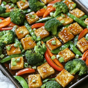 - 1 block (14 oz) firm tofu, drained and pressed - ¼ cup low-sodium soy sauce - 2 tablespoons honey or maple syrup - 2 tablespoons rice vinegar - 2 tablespoons sesame oil These ingredients form the heart of your dish. The firm tofu gives the meal its base and protein. Low-sodium soy sauce offers a rich umami flavor without too much salt. Honey or maple syrup adds sweetness, while rice vinegar adds a touch of tang. Lastly, sesame oil provides a nutty aroma that ties everything together. - 2 cups broccoli florets - 1 red bell pepper, sliced - 1 carrot, thinly sliced - 1 cup snap peas The veggies bring color and crunch. Broccoli florets add a hearty bite. Red bell pepper contributes sweetness and vibrancy. Carrots add a nice crunch, while snap peas bring a fresh snap. Together, these vegetables create a colorful spread that looks as good as it tastes. - 2 tablespoons sesame seeds (for garnish) - 2 green onions, chopped (for garnish) These garnishes are not just for looks; they add flavor and texture. Sesame seeds add a delightful crunch. Green onions bring a fresh, mild onion flavor. Using these garnishes makes your dish pop and look gourmet. You can enjoy your teriyaki tofu and veggies with or without them, but they elevate the meal. First, preheat your oven to 400°F (200°C). This helps cook everything evenly. Next, line a large sheet pan with parchment paper. This makes clean-up easy. Now, it’s time to cut the tofu. Drain and press the block of firm tofu to remove excess water. Then, cut it into bite-sized cubes. Place the tofu cubes in a medium bowl. While you're at it, prepare the vegetables. Slice the red bell pepper and thinly slice the carrot. Cut the broccoli into florets. Finally, gather the snap peas. You want a colorful mix for a vibrant dish! In a small bowl, mix the teriyaki sauce ingredients. Combine the low-sodium soy sauce, honey or maple syrup, rice vinegar, sesame oil, grated ginger, and minced garlic. Whisk until well combined. Pour half of this sauce over the tofu cubes. Let them marinate for about 15 minutes. This allows the tofu to soak up the flavors. Remember, reserve the other half of the sauce for later! Once the tofu has marinated, it’s time to arrange everything on the sheet pan. First, place the prepared vegetables on one side of the pan. Then, add the marinated tofu on the other side. Drizzle the reserved teriyaki sauce over both the tofu and veggies. Make sure everything is evenly coated. This ensures every bite is packed with flavor! Now, it’s time to bake! Place the sheet pan in the preheated oven. Bake for 25-30 minutes. This allows the tofu to turn golden and crispy. Don’t forget to stir everything halfway through. This step helps the tofu and veggies cook evenly. After baking, you’ll have a delicious meal ready to enjoy! How to get crispy tofu To get crispy tofu, start by pressing it well. Remove as much water as you can. Cut the tofu into bite-sized cubes. Marinate it in the teriyaki sauce for about 15 minutes. This step helps the tofu absorb flavor. When you bake it, use a hot oven. A temperature of 400°F (200°C) works best. Bake it until golden brown, which usually takes 25 to 30 minutes. Don't forget to stir halfway through to ensure even cooking. Best practices for tender vegetables For tender veggies, cut them into uniform sizes. This ensures they cook evenly. Broccoli, bell peppers, carrots, and snap peas are great choices. Place the veggies on one side of the pan. Drizzle them with some teriyaki sauce before baking. This adds flavor while keeping them crisp yet tender. Ideas for rice or grain pairings Serve your teriyaki tofu and veggies over rice or quinoa. Both options soak up the sauce nicely. Brown rice or jasmine rice adds a nutty flavor. Quinoa offers a protein boost and a slightly chewy texture. If you prefer, try cauliflower rice for a low-carb option. Ways to enhance flavor with extra toppings Boost flavor with toppings like sesame seeds and chopped green onions. These add crunch and freshness. You can also sprinkle some crushed red pepper for a kick. If you like nuts, try adding chopped peanuts or cashews for added texture. Recommended pans and utensils A large sheet pan is essential for this recipe. Use parchment paper for easy clean-up. A sharp knife will help with cutting veggies and tofu. A medium bowl is perfect for marinating the tofu. Kitchen gadgets for ease of preparation Consider using a tofu press to remove water easily. A whisk will help mix the sauce well. If you have a spatula, it helps with stirring the tofu and veggies on the pan. These tools will make your cooking process smooth and fun! {{image_2}} You can easily change the veggies in this recipe. Some great choices include: - Cauliflower florets - Zucchini slices - Bell peppers of different colors - Asparagus spears - Mushrooms These swaps keep the dish fresh and exciting. You can also try different sauces. If you want a kick, use sriracha instead of honey. For a sweeter taste, try agave syrup. If you need a gluten-free option, use tamari instead of soy sauce. Tamari has a similar taste and works well. You can also skip the honey and use maple syrup for a vegan dish. This keeps the meal plant-based and tasty. For larger groups, simply double or triple the ingredients. Use multiple sheet pans if needed. This recipe is great for meal prep too. You can store leftovers in containers and enjoy them later. Just reheat in the oven or microwave for a quick meal. To keep your leftovers fresh, use airtight containers. Glass or BPA-free plastic containers work best. Store your teriyaki tofu and veggies in the fridge for up to three days. This keeps the flavors intact and the tofu nice. Reheat your leftovers in the oven or on the stovetop. The oven helps maintain the tofu's crispiness. Preheat the oven to 350°F (175°C) and bake for about 10-15 minutes. On the stovetop, warm it gently in a pan over medium heat. Add a splash of water or sauce to keep it moist. Serve over rice or quinoa for a quick meal. You can freeze the dish for longer storage. Make sure to let it cool first. Place it in a freezer-safe container or bag. It can stay frozen for up to three months. When you’re ready to eat, thaw it in the fridge overnight. Reheat it in the oven or stovetop as mentioned before. This will help maintain the best quality and texture. If you want to skip tofu, try tempeh or chickpeas. Tempeh has a nutty taste. It also holds flavor well. Chickpeas add protein and a creamy texture. You can use seitan for a chewy bite. Each option makes your meal tasty. This dish takes about 45 minutes total. You spend 15 minutes prepping. This includes cutting tofu and veggies. Cooking takes around 25 to 30 minutes in the oven. This time gives you a warm, tasty meal. Yes, feel free to spice it up! Add red pepper flakes for heat. You can mix in five-spice powder for depth. Garlic powder or onion powder also works well. Experiment with flavors to find your favorite mix. Absolutely! This dish is great for meal prep. You can make it ahead and store it. Use airtight containers to keep it fresh. Reheat portions easily for quick lunches or dinners. This makes your week simpler. This blog post shows you how to make a tasty teriyaki tofu dish. We discussed essential ingredients, including firm tofu and vibrant vegetables. I outlined clear steps, from prepping ingredients to baking everything just right. You learned tips for a crispy texture and serving suggestions. Experiment with substitutions and make this meal your own. Storing leftovers is easy, and reheating keeps it delicious. Dive in and enjoy your healthy creation!