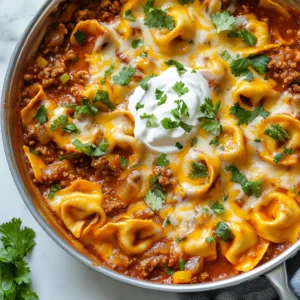 - 1 lb ground beef - 1 small onion, diced - 2 cloves garlic, minced - 1 cup enchilada sauce (red or green) - 1 cup shredded cheddar cheese - 1 cup prepared cheese tortellini - 1 teaspoon ground cumin - 1 teaspoon chili powder - Salt and pepper to taste - Fresh cilantro, chopped (for garnish) - Sour cream (optional, for serving) You can change this dish to fit your taste. Here are some ideas: - Use ground turkey or chicken instead of beef for a lighter option. - Add black beans or corn for extra texture and flavor. - Mix in diced bell peppers for added crunch. - Use different cheeses like Monterey Jack or pepper jack for a twist. I suggest using specific brands for great taste. For enchilada sauce, I like Herdez or Old El Paso. They both offer good flavor. For tortellini, Bertolli or Rana make tasty options. Their cheese tortellini cooks well and adds creaminess. {{ingredient_image_1}} Start by heating a large skillet over medium heat. Add 1 pound of ground beef. Cook the beef until it turns brown. Use a spatula to break it into smaller pieces. If there is extra fat, drain it. Next, add 1 small diced onion and 2 minced garlic cloves. Cook these for about 3 to 4 minutes. You want the onion to become soft and fragrant. Now, stir in 1 cup of enchilada sauce, 1 teaspoon of ground cumin, 1 teaspoon of chili powder, salt, and pepper. Let the mixture simmer for about 5 minutes. This step builds rich flavors in your beef. While the beef simmers, grab a pot of boiling water. Add 1 cup of prepared cheese tortellini. Cook it according to the package instructions until it is tender. Once done, drain the tortellini and set it aside. Make sure not to overcook it. Perfect tortellini should be soft but not mushy. This will help maintain the dish's texture. Now that the beef mixture is ready, it's time to combine everything. Gently fold the cooked tortellini into the beef mixture. Add ½ cup of the shredded cheddar cheese and mix well. Reduce the heat to low. Sprinkle the remaining cheese on top. Cover the skillet with a lid and let it sit for 2 to 3 minutes. This allows the cheese to melt and become bubbly. Finally, remove from heat and sprinkle fresh cilantro on top. Your Beef Enchilada Tortellini is now ready to serve! When cooking ground beef, use medium heat. This helps the beef brown well. Break up the meat with a spatula. Cook until it turns a nice brown color. Drain any excess fat. This keeps your dish lighter and less greasy. To cook tortellini, follow the package instructions. Bring a pot of salted water to a boil. Add the tortellini and cook until they float. This usually takes about 3-5 minutes. Drain them gently and set aside. This keeps them from getting mushy. Adjust the seasonings to fit your taste. If you like more heat, add extra chili powder. Fresh herbs like cilantro can add a fresh touch. You can even try lime juice for a zesty kick. Taste as you go, and make it your own! Pro Tips Use Lean Ground Beef: For a healthier option, opt for lean ground beef (90% or higher) to reduce the fat content in the dish. Customize Your Cheese: Feel free to experiment with different types of cheese, such as pepper jack for a spicy kick or mozzarella for a milder flavor. Add Vegetables: Incorporate diced bell peppers, zucchini, or corn into the beef mixture for added nutrition and flavor. Serve with Fresh Sides: Complement your dish with a side of Mexican rice or a fresh salad to round out the meal. {{image_2}} You can make this dish vegetarian by using lentils or black beans instead of ground beef. Both options add great texture and flavor. Cook the lentils first until they are tender. For black beans, simply drain and rinse them. Mix the beans or lentils with onions and spices just like you would with beef. This keeps the dish hearty and satisfying. If you like heat, this dish can be spiced up easily. You can add diced jalapeños or a dash of hot sauce to the beef mixture. For an extra kick, sprinkle some cayenne pepper or red pepper flakes. Adjust the heat to your taste. This version will leave your taste buds dancing! Cheese can take this dish to the next level. Try adding pepper jack cheese for a creamy texture with a hint of spice. You can also mix in some mozzarella for a gooey finish. Top with more cheddar cheese as it melts for a beautiful, cheesy crust. This will please any cheese lover! To store leftovers, let the dish cool to room temperature. Then, place it in an airtight container. This keeps the flavors fresh and prevents odors from mixing. Store it in the fridge for up to three days. If you want to keep it longer, consider freezing. When you’re ready to eat your leftovers, reheat them gently. You can use the microwave or the stove. If using the microwave, cover the dish with a microwave-safe lid. Heat it for about two minutes, stirring halfway. On the stove, warm it over low heat. Add a splash of water to keep it moist. To freeze this dish, follow the cooling steps first. Use a freezer-safe container or a heavy-duty freezer bag. Remove as much air as possible to prevent freezer burn. It can last in the freezer for up to three months. When you want to enjoy it, thaw it in the fridge overnight before reheating. Yes, you can. Ground turkey or chicken works well. You can also try beans for a vegetarian option. Each protein adds its own flavor. Adjust your seasoning to match the protein you choose. I recommend using either red or green enchilada sauce. Red sauce gives a rich, bold flavor. Green sauce offers a fresher, slightly tangy taste. Both options work great in this dish. Your choice depends on your flavor preference. Yes, you can prepare it ahead. Cook the beef and mix with tortellini. Store it in the fridge for up to two days. When ready to serve, just reheat and melt the cheese. This makes for an easy dinner on busy nights. You can create a delicious meal with our step-by-step guide. We covered all the key ingredients, from beef and tortellini to tasty sauces. You can even customize your dish with extra flavors or options for vegetarians. Remember to store and reheat leftovers properly to enjoy later. Cooking is fun and easy when you follow these tips. With practice, you will make this meal a family favorite. Embrace your kitchen adventure and enjoy every bite!