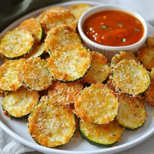 To make crispy air fryer parmesan zucchini chips, gather these simple ingredients: - 2 medium zucchinis, sliced thinly into rounds - ½ cup grated Parmesan cheese - ½ cup breadcrumbs (preferably panko for extra crunch) - 1 teaspoon garlic powder - 1 teaspoon Italian seasoning - Salt and pepper to taste - 1 tablespoon olive oil - Cooking spray These ingredients come together to create a tasty and healthy snack. The zucchini gives a fresh flavor, while the Parmesan and breadcrumbs add a crispy texture. Garlic powder and Italian seasoning boost the taste even more. Olive oil helps everything stick and adds richness. Make sure you have cooking spray on hand to enhance crispiness. Each ingredient plays a key role in making your chips delicious and satisfying. {{ingredient_image_1}} Preheating your air fryer is key. It helps the zucchini cook evenly and get crispy. Set your air fryer to 375°F (190°C) and let it warm up for about 3-5 minutes. This small step makes a big difference in the final crunch. Slice the zucchini thinly into rounds. Aim for about ¼ inch thick. This thickness gives the best crunch. Next, drizzle the olive oil over the slices. Toss them gently so every piece gets coated. This adds flavor and aids in crispiness. In a large bowl, mix the grated Parmesan cheese, breadcrumbs, garlic powder, Italian seasoning, salt, and pepper. Stir well to combine. You can adjust the seasonings based on your taste. Want it spicier? Add some red pepper flakes. This mix creates a tasty coating that sticks well. When you’re ready, take each zucchini slice and dip it into the Parmesan mixture. Make sure it is fully covered. Place the coated slices in the air fryer basket in a single layer. Leave space between each piece to allow hot air to circulate. You might need to cook in batches if your fryer is small. Lightly spray the tops with cooking spray to boost crispiness. Cook the zucchini chips for 10-12 minutes. Halfway through, turn them for even browning. Keep an eye on them as cooking times can vary by model. When they are golden brown, carefully remove them and let them cool before serving. - Olive Oil Techniques: Use just one tablespoon of olive oil. Drizzle it over the sliced zucchini. Toss the slices gently to coat them evenly. This step is key for crispiness. - Cooking Spray Usage: After coating, lightly spray the tops of the zucchini chips with cooking spray. This adds an extra crunch. It helps the cheese and breadcrumbs crisp up nicely in the air fryer. - Overcrowding the Basket: Do not pile the zucchini slices in the basket. Leave space between each piece. This allows hot air to circulate. It ensures even cooking and perfect crispness. - Incorrect Temperature: Always preheat your air fryer to 375°F (190°C). Cooking at the right temperature makes a big difference. Lower temperatures can lead to soggy chips. - Dipping Sauce Ideas: Try serving these zucchini chips with marinara sauce or ranch dressing. A spicy aioli can also add great flavor. - Pairing with Other Dishes: Serve them as a side with grilled chicken. They also work well as a snack during movie night. Enjoy them any time you crave a crunchy treat! Pro Tips Slice Evenly: Make sure to slice the zucchini into uniform thickness to ensure even cooking and crispiness. Experiment with Seasonings: Feel free to add your favorite spices or herbs to the breadcrumb mixture for a personalized flavor. Check for Doneness: Keep an eye on the chips during cooking, as air fryer models may vary in cooking time. They should be golden brown and crispy. Serve Immediately: These chips are best enjoyed fresh and hot. If you need to make them ahead, reheat them briefly in the air fryer for extra crispiness. {{image_2}} You can make these zucchini chips even more fun! Here are a couple of ideas: - Adding Spices: Spice things up by adding cayenne pepper for heat. You can also use smoked paprika for a deeper flavor. Just sprinkle in about half a teaspoon when mixing your coating. This small change can make a big impact! - Using Different Cheeses: While Parmesan shines in this recipe, other cheeses can work well too. Try using cheddar for a sharper taste or mozzarella for that gooey pull when they come out of the air fryer. Just remember to adjust the amount based on the cheese's strength. If you want to try something different, here are two great options: - Oven-Baked Version: Preheat your oven to 425°F (220°C). Place the coated zucchini slices on a baking sheet lined with parchment paper. Bake for about 20-25 minutes, flipping halfway through. This method gives you crispy chips too, just like the air fryer! - Using Other Vegetables: You don’t have to stick with zucchini. Try using eggplant, sweet potatoes, or even carrots. Just slice them thin, coat them the same way, and follow the same cooking method. Each veggie brings its own taste and texture for a fresh twist! To keep your leftover zucchini chips fresh, store them in an airtight container. Line the bottom of the container with paper towels to soak up any moisture. This helps maintain their crispiness. Place the chips in a single layer if possible. If you have many chips, stack them with more paper towels in between. For reheating, use the air fryer or an oven. Preheat your air fryer to 350°F (175°C). Place the chips in a single layer and heat for about 3-5 minutes. Check them often to avoid burning. In the oven, spread them out on a baking sheet and heat for 5-7 minutes at 350°F (175°C). Zucchini chips can last about 3-5 days in the fridge. Make sure they are sealed well to stay crisp. If you want them to last longer, consider freezing. For freezing, place the cooled zucchini chips in a freezer-safe bag. Remove as much air as possible before sealing. They can last up to 2-3 months in the freezer. When ready to eat, reheat them in the air fryer or oven for the best texture. Yes, you can make these zucchini chips gluten-free. To do this, simply swap out the breadcrumbs for gluten-free alternatives. Here are some recommended substitutes: - Gluten-free breadcrumbs: These are available in most stores. - Ground almonds: They add a nice crunch and flavor. - Cornmeal: This will give a different texture but works well. These zucchini chips pair well with a variety of dips. Here are some of the best pairings: - Marinara sauce: The classic choice for dipping. - Ranch dressing: A creamy option that adds flavor. - Hummus: A healthy and tasty choice. You can still enjoy zucchini chips without an air fryer. Here are some alternative cooking techniques: - Oven-baked: Preheat your oven to 425°F (220°C). Place the coated zucchini chips on a baking sheet. Bake for 20-25 minutes, flipping halfway through. - Pan-frying: Heat oil in a skillet over medium heat. Fry the zucchini chips in batches for 3-4 minutes on each side until golden. In this post, we explored how to make delicious air fryer Parmesan zucchini chips. We covered key ingredients, step-by-step instructions, tips for crispy results, and even variations to try. Remember, preheating your air fryer and avoiding overcrowding are crucial for success. Use different cheeses or spices for a fun twist, and don't forget about great serving options. With proper storage, your leftover chips will stay fresh. Now, it's time to enjoy those crunchy treats! Dive in and savor every bite.